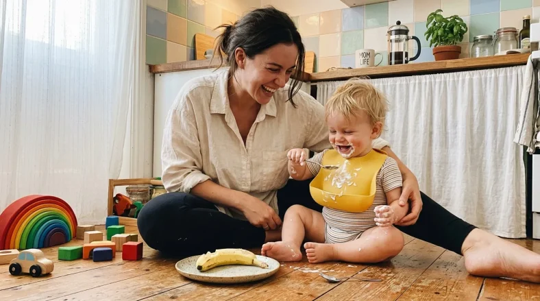Une mère souriante joue avec son jeune enfant dans une cuisine