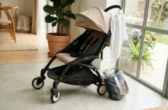 Poussette beige et noire près de portes vitrées avec plante