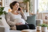 Personne enceinte au téléphone, calme et attentive, dans un intérieur lumineux
