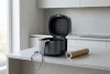 Un air fryer générique ouvert et vide côtoie un rouleau d'aluminium encore dans son tube.