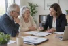 Senior et proche échangeant avec une conseillère autour de documents génériques
