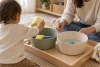 Jeune enfant réalisant une activité de transvasement avec un adulte